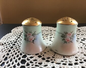 Puede incluir: Un par de saleros y pimenteros vintage con un esmalte verde claro y rosas rosas pintadas a mano. Los saleros tienen tapas doradas con agujeros para dispensar sal y pimienta.