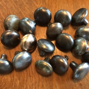 以下が含まれることがあります： さまざまなグレーとシルバーの色合いの、18個の楕円形の金属製キャビネットノブのセットです。