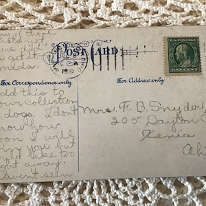 May include: A vintage postcard with a handwritten message. The postcard is addressed to Mrs. F. B. Snyder, 205 Dayton Ave, Xenia, Ohio. The message reads: "Add this to your collection of dogs. I don't know how soon I will find you but would like to right away. I haven't seen..."