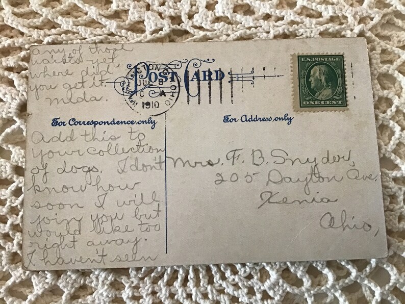 May include: A vintage postcard with a handwritten message. The postcard is addressed to Mrs. F. B. Snyder, 205 Dayton Ave, Xenia, Ohio. The message reads: "Add this to your collection of dogs. I don't know how soon I will find you but would like to right away. I haven't seen..."