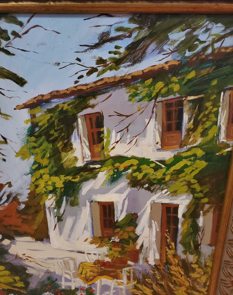 Puede incluir: Una pintura de una casa blanca con enredaderas verdes que crecen por el lado. La casa tiene tres ventanas con contraventanas marrones. Hay sillas blancas y una mesa con un mantel amarillo delante de la casa.