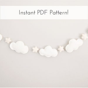May include: A white felt cloud and star garland. The garland features soft, puffy clouds and star shapes strung together on a thin white cord. The text "Instant PDF Pattern!" is displayed in a white rectangle.