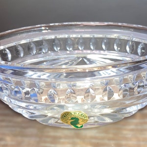 Puede incluir: Un cuenco de vidrio transparente con un patr&oacute;n decorativo de peque&ntilde;os c&iacute;rculos y &oacute;valos. El cuenco tiene una pegatina dorada en la parte inferior con el texto "Waterford Crystal" y un logotipo de caballito de mar.
