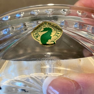 Puede incluir: Primer plano de una pegatina de Waterford Crystal con fondo dorado y logotipo de caballito de mar verde. La pegatina dice "Waterford Crystal Hecho en Alemania".