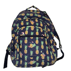 May include: A navy blue backpack with a quilted pattern featuring yellow pineapples and green leaves. The backpack has a front pocket, black straps, and a top handle. The design includes tropical drink and flamingo accents.