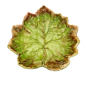 May include: A decorative leaf-shaped dish with a detailed vein pattern. The ceramic dish features a gradient of green and brown hues, creating a naturalistic appearance. This unique piece is ideal for serving or display.