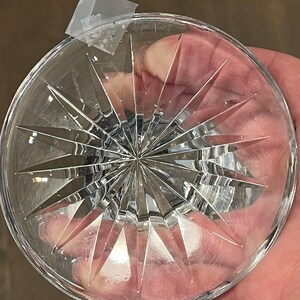 May include: The bottom of a clear crystal glass with a starburst pattern.