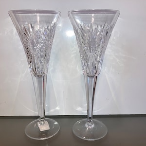 Puede incluir: Dos copas de champán de cristal transparente con un diseño de cristal tallado. Las copas tienen un tallo alto y delgado y una copa ancha y poco profunda.