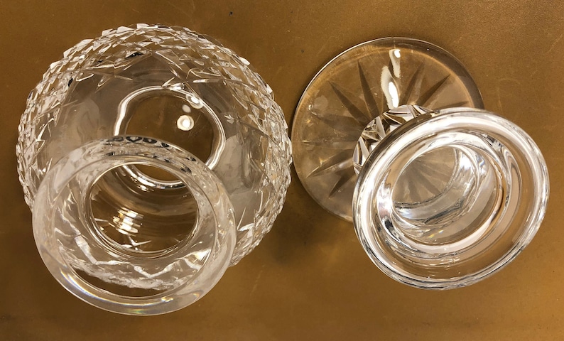 May include: Two clear glass candle holders, one with a round base and the other with a flared base. Both have a cut glass design.
