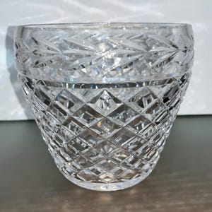 May include: A clear glass bowl with a diamond pattern. The bowl is made of cut glass and has a wide, round shape.