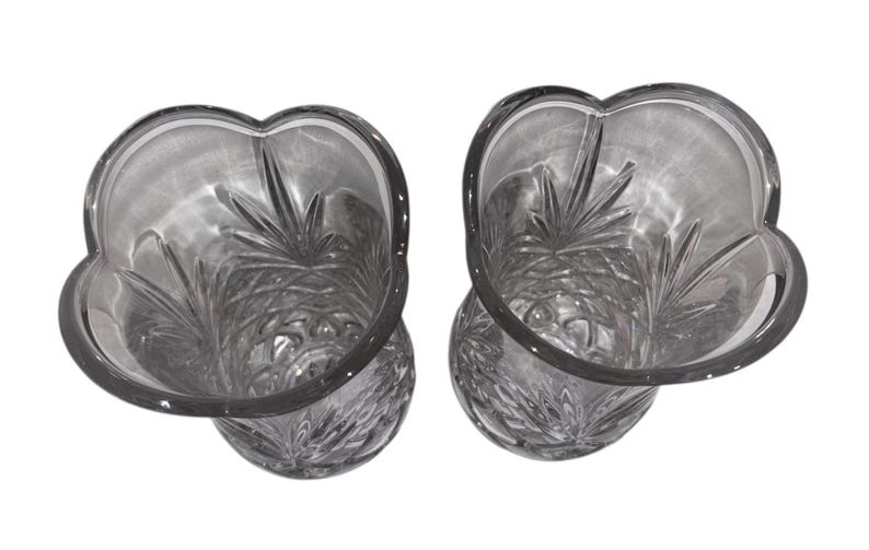 May include: Two clear glass vases with a unique, petal-shaped rim. The vases have a detailed, etched design on the interior, creating a textured appearance. The glass is transparent, allowing light to pass through, and the vases are set against a white background.