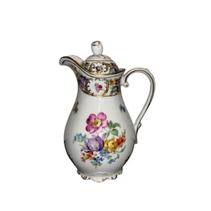 May include: White porcelain pitcher with a lid, adorned with colorful floral designs. The pitcher features a curved handle and a spout, with gold trim accents. The floral pattern includes pink, purple, yellow, and blue flowers.