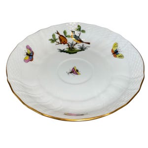 May include: White porcelain saucer with a gold rim and a textured surface. The saucer features colorful illustrations of birds and butterflies. The center of the saucer has a small butterfly illustration.
