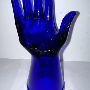 Peut inclure: Une sculpture de main en verre bleu cobalt. La main est ouverte et les doigts sont &eacute;cart&eacute;s. La main est fix&eacute;e &agrave; une base &eacute;galement en verre bleu cobalt.