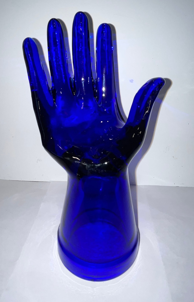 Peut inclure: Une sculpture de main en verre bleu cobalt. La main est ouverte et les doigts sont &eacute;cart&eacute;s. La main est fix&eacute;e &agrave; une base &eacute;galement en verre bleu cobalt.