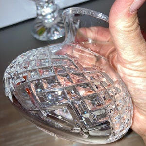 May include: A clear glass vase with a diamond pattern. The vase is empty and has a round base.