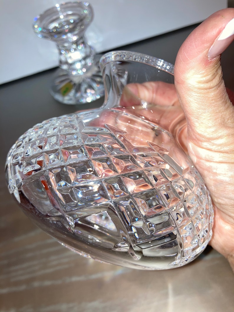 May include: A clear glass vase with a diamond pattern. The vase is empty and has a round base.