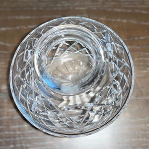 以下が含まれることがあります： 透明なカットガラスのボウルで、ダイヤモンド模様が施されています。ボウルは円形で、中央は小さくくぼんでいます。ガラスは光を反射し、キラキラとした効果を生み出します。ボウルは装飾目的またはサービングに使用される可能性があります。