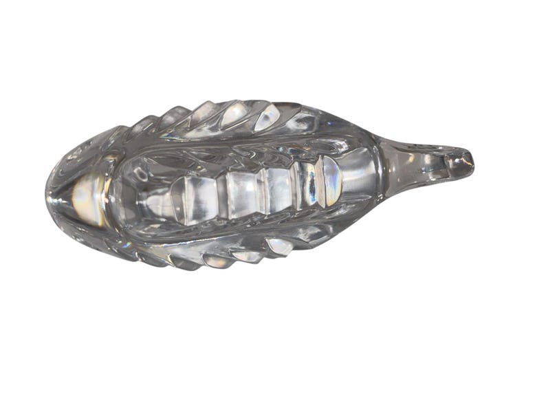 K&ouml;nnte beinhalten: Eine klare Glasschiffchen mit einem strukturierten, blattartigen Design. Das Schiffchen hat einen langen, spitzen Ausguss und einen breiten, oval geformten K&ouml;rper. Das Glas ist transparent und l&auml;sst Licht durch.