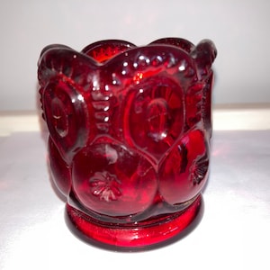 Op de afbeelding: Een robijnrode glazen votiefkaarsenhouder. De houder heeft een ster- en maanontwerp. Het glas is dieprood van kleur en heeft een glanzende afwerking. De kaarsenhouder is een decoratief item.