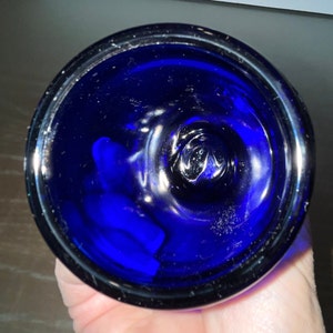 Peut inclure: Un bouchon de bouteille en verre bleu cobalt avec un dessus lisse et arrondi. Le bouchon pr&eacute;sente une l&eacute;g&egrave;re indentation au centre.