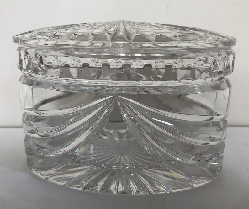 May include: A clear glass jar with a lid, both featuring intricate cut-glass designs. The jar is round and has a wide opening.