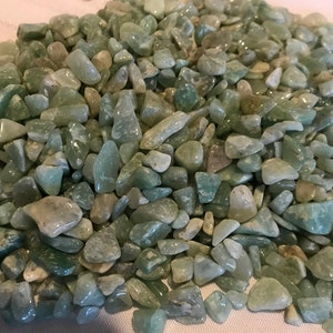 May include: A pile of small, light green and white tumbled stones. The stones are smooth and polished, and they have a natural, organic look.