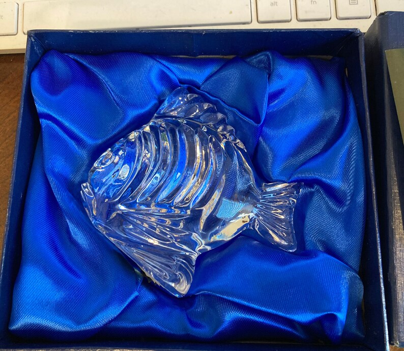 Peut inclure: Une figurine de poisson en verre transparent dans un coffret en velours bleu. Le poisson a un design d&eacute;taill&eacute; et est un objet d&eacute;coratif.