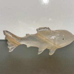 May include: A white and brown carved alabaster fish figurine. The fish has a detailed, realistic design and is a beautiful example of craftsmanship.
