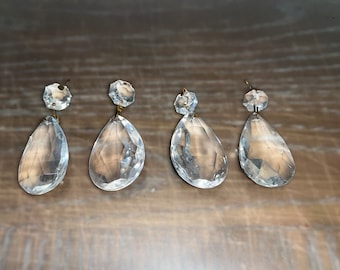 May include: Four clear glass teardrop-shaped crystal prisms with gold-toned metal accents. The prisms are hanging from a wire.