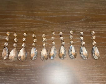 May include: Eight crystal teardrop-shaped chandelier prisms with gold-toned tops.