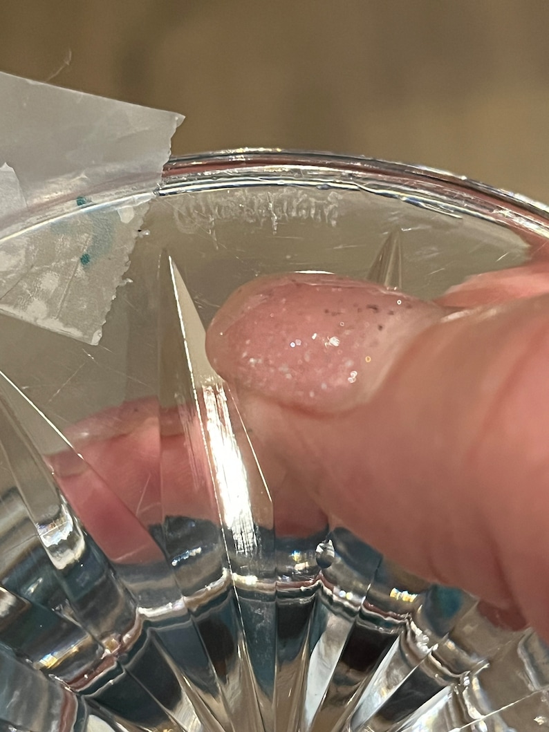 May include: Close-up of the bottom of a clear glass vase with a cut-glass design. The vase has a thick rim and a small amount of white residue on the bottom.