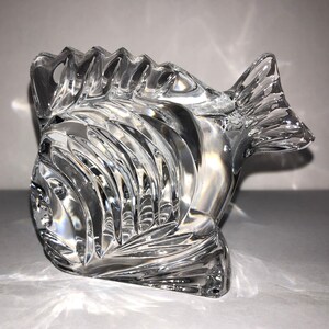 Peut inclure: Une figurine de poisson en cristal transparent avec un design textur&eacute; d&eacute;taill&eacute;. Le poisson a une grosse t&ecirc;te et une longue queue fluide.