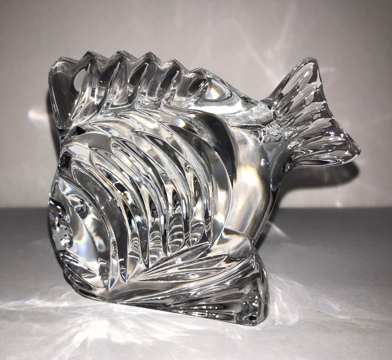 Peut inclure: Une figurine de poisson en cristal transparent avec un design textur&eacute; d&eacute;taill&eacute;. Le poisson a une grosse t&ecirc;te et une longue queue fluide.