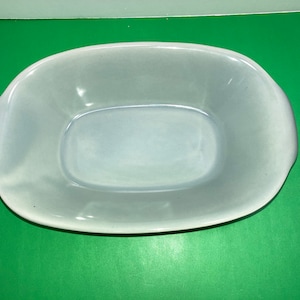 Op de afbeelding: Een lichtblauwe keramische serveerschaal met een licht ovale vorm. De schaal heeft een gladde, glanzende afwerking.