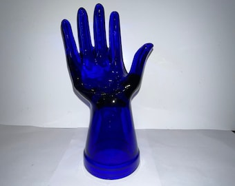 Peut inclure: Une sculpture de main en verre bleu cobalt. La main est levée, les doigts écartés. La main est fixée à une base également en verre bleu cobalt.