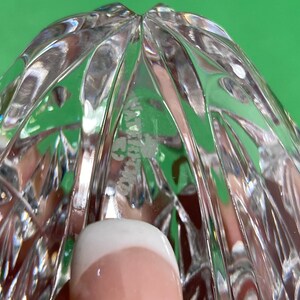 May include: Close-up of a clear crystal object with a cut pattern. The object has a rounded shape with a textured surface. The word "WATERFORD" is etched into the crystal.