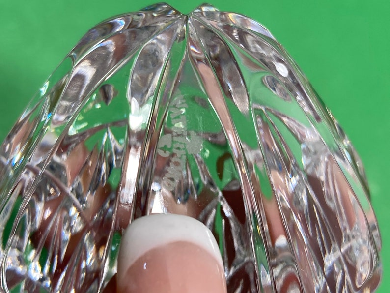 May include: Close-up of a clear crystal object with a cut pattern. The object has a rounded shape with a textured surface. The word "WATERFORD" is etched into the crystal.