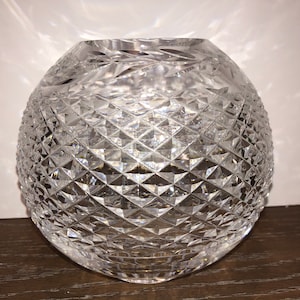 May include: A clear glass vase with a diamond pattern. The vase is round and has a wide opening.