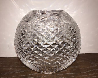 May include: A clear glass vase with a diamond pattern. The vase is round and has a wide opening.