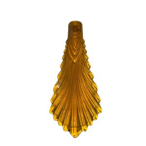 May include: A tall, amber-colored decorative vase with a unique, elongated shape. The vase features a series of vertical, ridged lines that create a textured, fan-like design. The vase is made of a transparent material, allowing light to pass through.