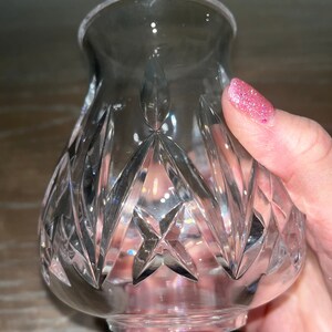 May include: A clear glass vase with a cut crystal design. The vase has a round base and a wide opening.