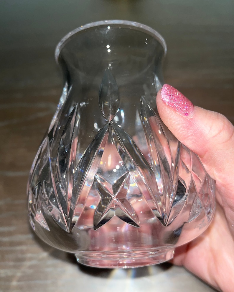 May include: A clear glass vase with a cut crystal design. The vase has a round base and a wide opening.