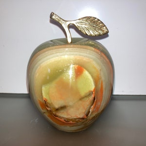 May include: A green, orange, and white marble apple with a gold leaf stem. The apple is a decorative object.