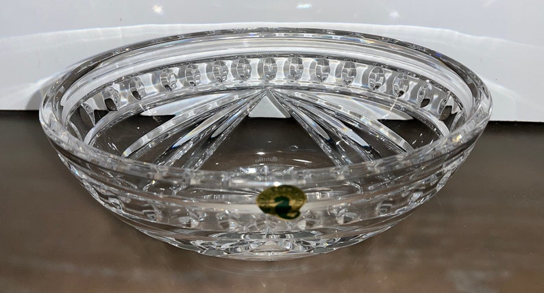 Puede incluir: Un cuenco de cristal transparente con un dise&ntilde;o de cristal tallado. El cuenco tiene una forma redonda y un borde ancho. El cuenco est&aacute; decorado con una pegatina verde con el n&uacute;mero "2" en ella.