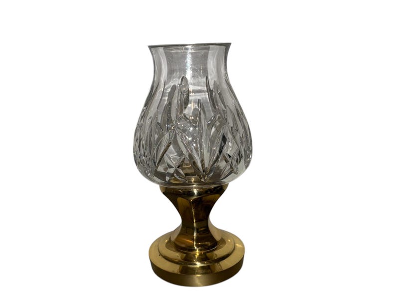 May include: A clear glass candle holder with a cut crystal design and a gold metal base.