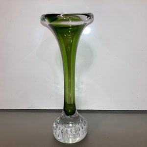 May include: A green glass vase with a flared opening and a round, textured base.