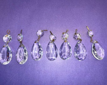 May include: Eight clear glass teardrop-shaped crystal prisms with gold-toned metal accents. The prisms have a faceted design and are hanging from a gold-toned metal loop.