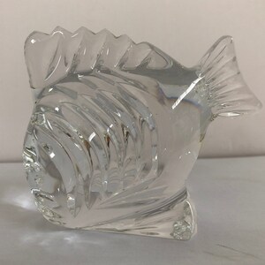 Peut inclure: Une sculpture de poisson en verre transparent avec un design textur&eacute; d&eacute;taill&eacute;. Le poisson est tourn&eacute; vers la gauche et a une nageoire sur le dos et une nageoire caudale.