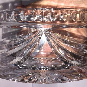 May include: A clear glass bowl with a decorative, cut-glass design. The bowl has a scalloped rim and a starburst pattern at the base.